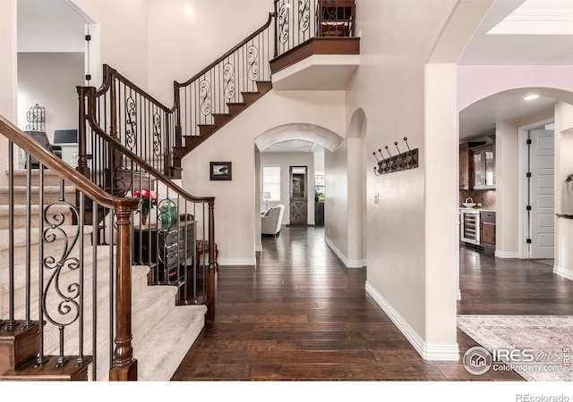foyer featuring wine cooler, baseboards, a high ceiling, and wood-type flooring