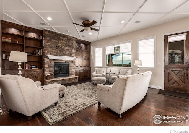 living room with dark wood-style flooring, a ceiling fan, recessed lighting, and a stone fireplace