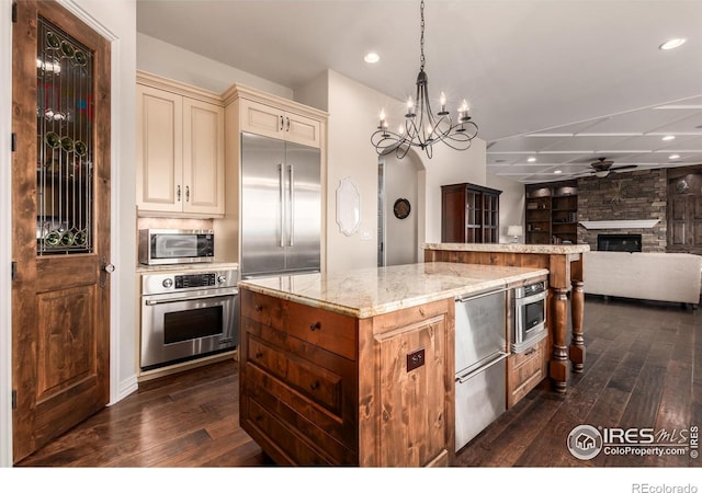 kitchen with dark wood-style flooring, a kitchen island, cream cabinetry, and stainless steel appliances