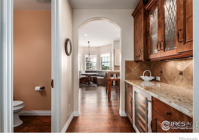 bar featuring arched walkways, decorative backsplash, wine cooler, dark wood-style floors, and a bar