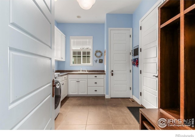 clothes washing area with washer and dryer, light tile patterned flooring, baseboards, a sink, and cabinet space