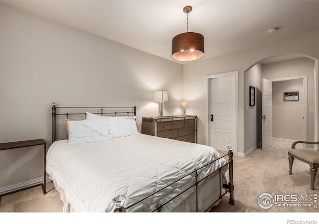 bedroom with arched walkways, baseboards, and light carpet