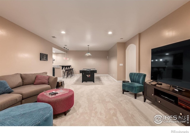 living area featuring arched walkways, baseboards, recessed lighting, and light carpet
