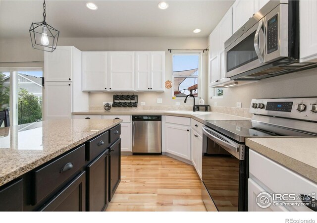 3803 Peach St, Wellington, CO 80549 - kitchen featuring appliances with stainless steel finishes, a sink, white cabinetry, light wood finished floors, and pendant lighting