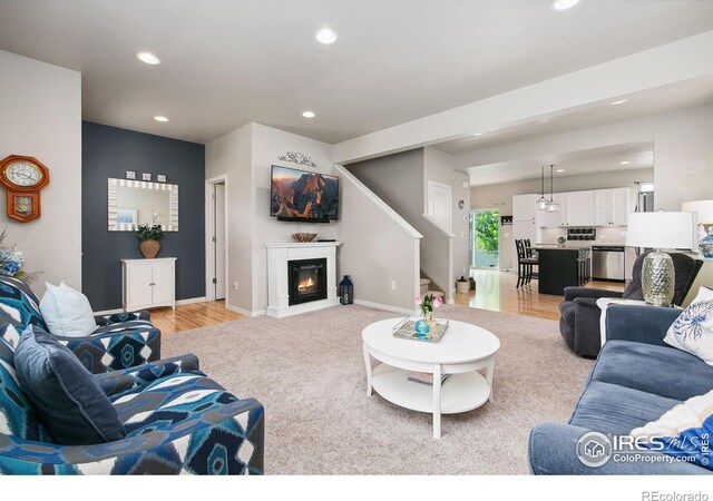 3803 Peach St, Wellington, CO 80549 - living room with recessed lighting, a glass covered fireplace, baseboards, light colored carpet, and stairway