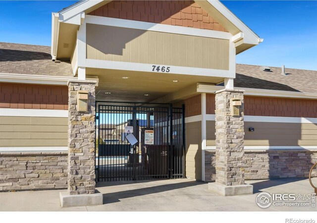 3803 Peach St, Wellington, CO 80549 - doorway to property featuring a shingled roof, a gate, and stone siding