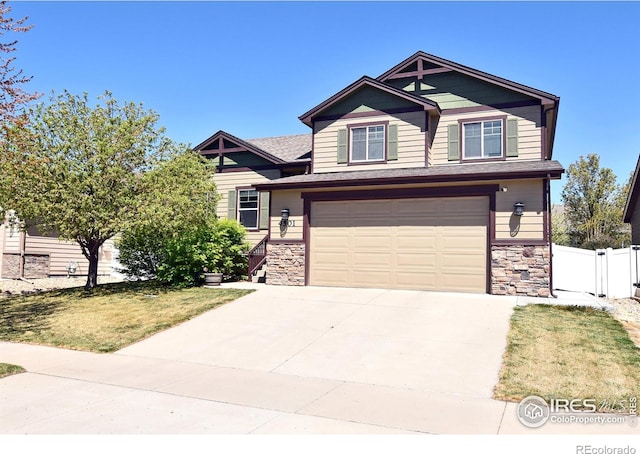 craftsman house featuring a garage, fence, a front yard, stone siding, and concrete driveway