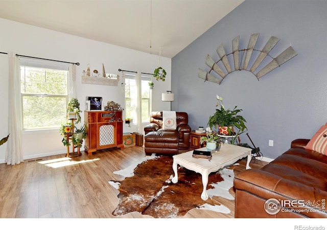 living room featuring baseboards, visible vents, wood finished floors, and lofted ceiling
