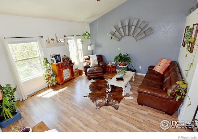living room featuring baseboards, visible vents, and wood finished floors