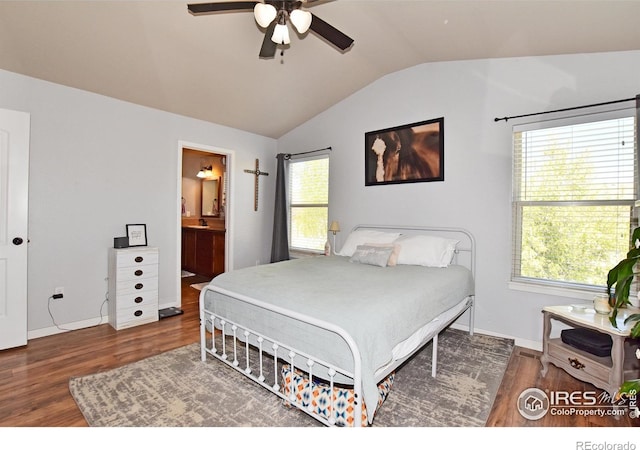 bedroom with ensuite bathroom, wood finished floors, vaulted ceiling, and multiple windows