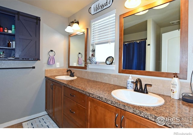 full bathroom with double vanity, baseboards, visible vents, and a sink