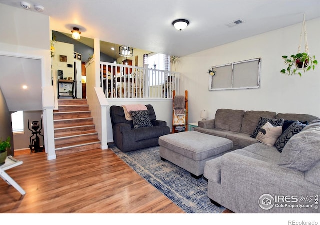 living room featuring visible vents, wood finished floors, and stairway