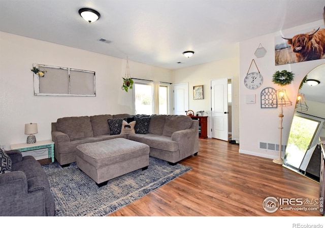 living area featuring visible vents, plenty of natural light, and wood finished floors