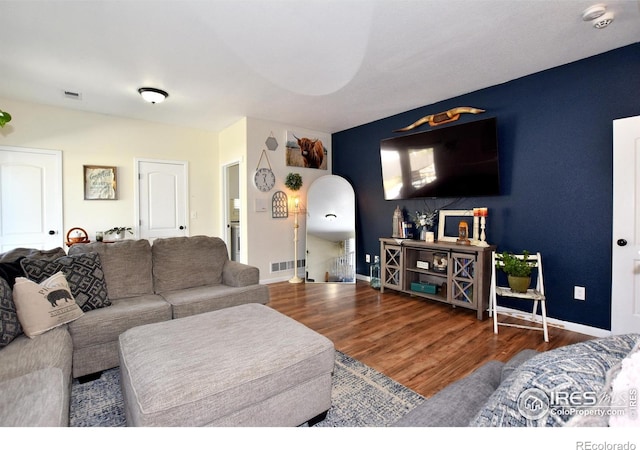 living room with baseboards, arched walkways, wood finished floors, and visible vents