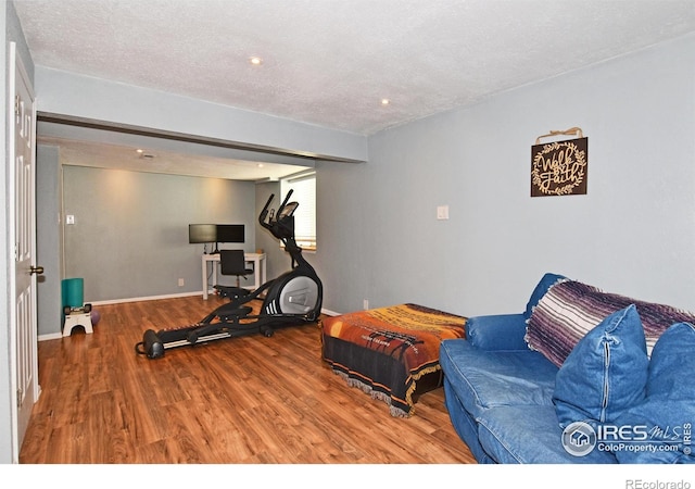 workout room featuring baseboards, recessed lighting, a textured ceiling, and wood finished floors