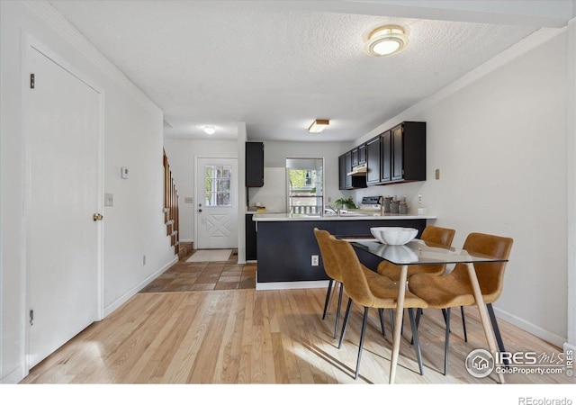 dining area with light wood-style floors, baseboards, ornamental molding, and stairway
