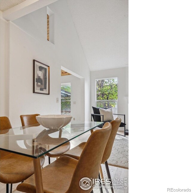 dining room with light wood-style flooring and high vaulted ceiling