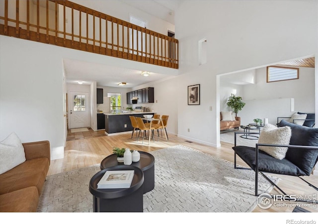 living room featuring baseboards, a high ceiling, and light wood-type flooring