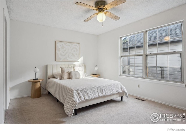 carpeted bedroom featuring baseboards, a ceiling fan, a textured ceiling, and visible vents