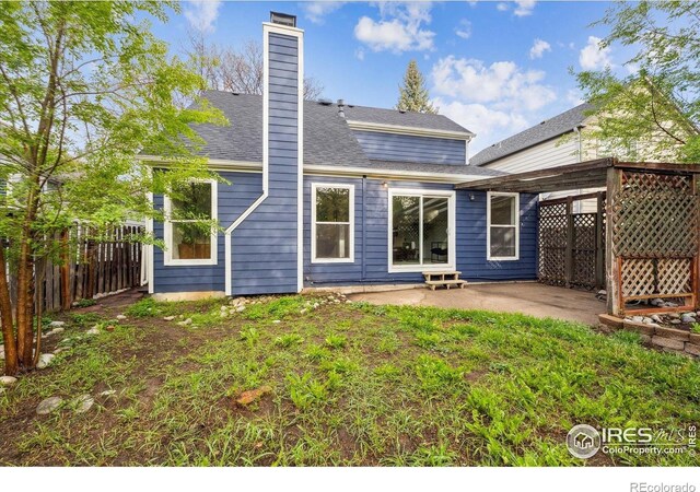 back of property featuring fence, a chimney, and a patio area