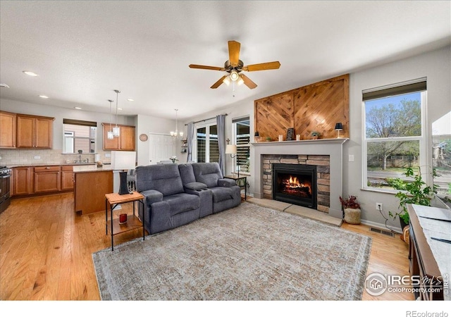 living area featuring light wood-style flooring, a ceiling fan, a fireplace, visible vents, and recessed lighting