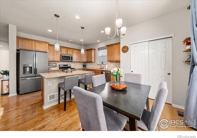 dining area featuring visible vents, light wood-style flooring, recessed lighting, and a chandelier