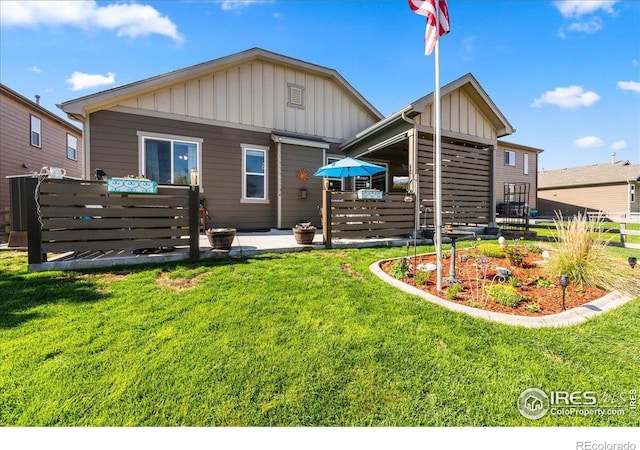back of property with board and batten siding, a yard, and fence