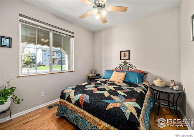 bedroom with ceiling fan, baseboards, visible vents, and wood finished floors