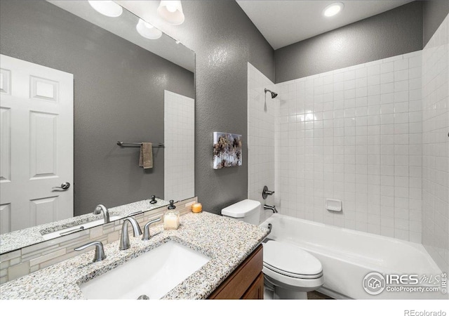 full bathroom featuring vanity, toilet, a textured wall, and bathing tub / shower combination