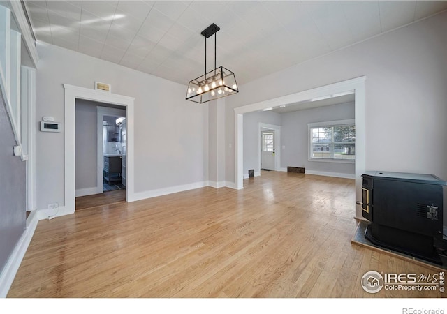 405 Maple St, Fort Morgan, CO 80701 - unfurnished dining area with a wood stove, light wood-style flooring, a chandelier, and baseboards