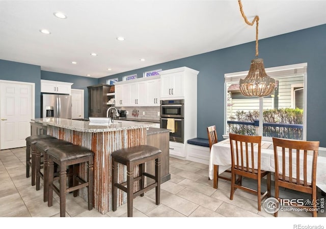 kitchen with white cabinets, stainless steel appliances, an inviting chandelier, and light tile patterned floors