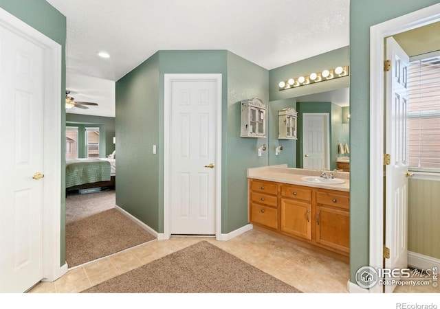ensuite bathroom featuring tile patterned flooring, vanity, baseboards, ceiling fan, and connected bathroom