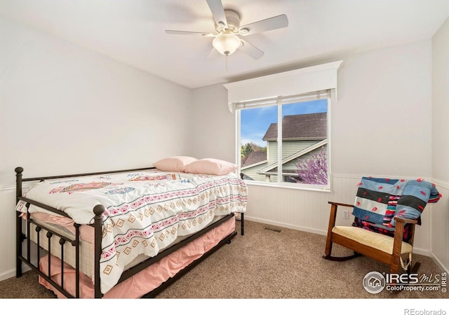 bedroom with visible vents, a ceiling fan, carpet, and a wainscoted wall