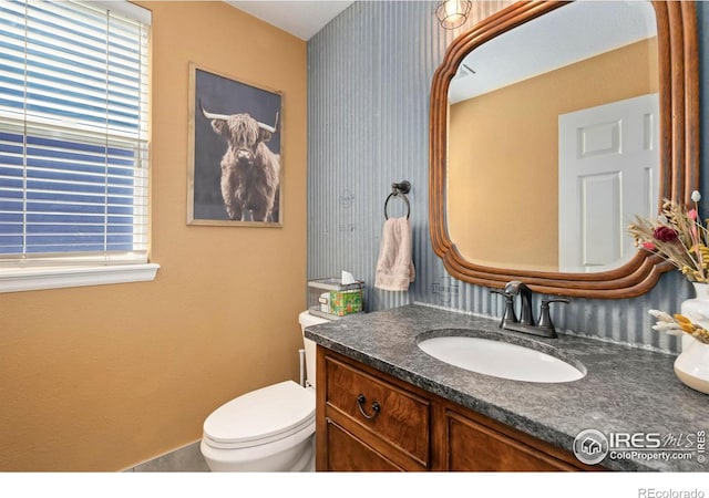 bathroom featuring toilet, wallpapered walls, a wealth of natural light, and vanity