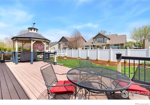 wooden terrace featuring a gazebo, a fenced backyard, a lawn, and outdoor dining space