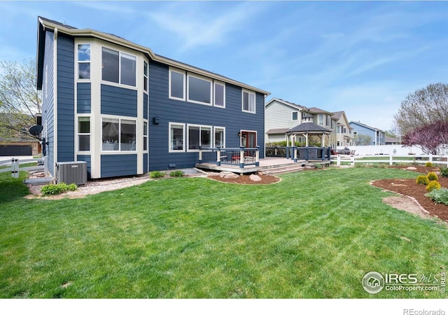 rear view of property featuring fence, a wooden deck, a gazebo, and a yard