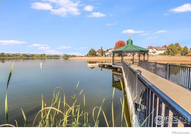 dock area with a water view, a gazebo, and fence