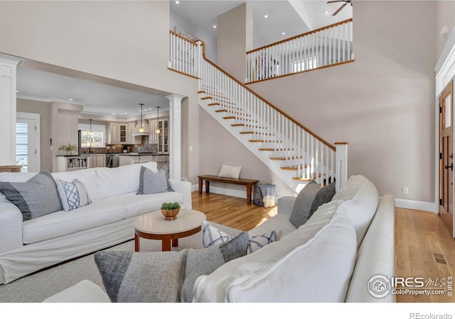 living area featuring light wood-style floors, a high ceiling, recessed lighting, and stairs