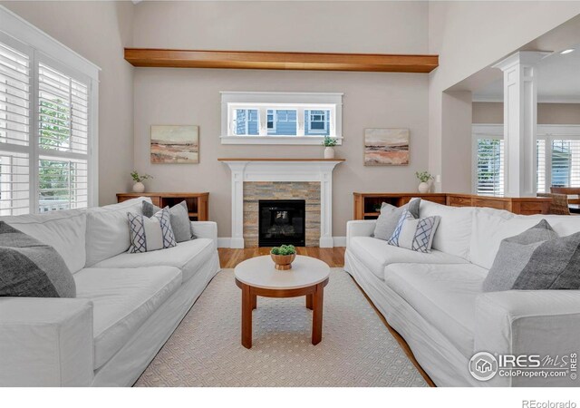 living area with decorative columns, wood finished floors, and a fireplace
