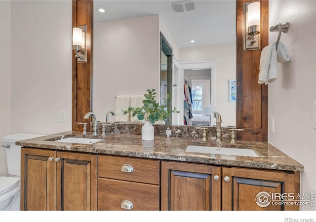 bathroom with ensuite bathroom, a sink, visible vents, and toilet