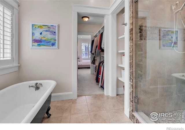 ensuite bathroom featuring a freestanding tub, tile patterned flooring, a shower stall, baseboards, and ensuite bathroom