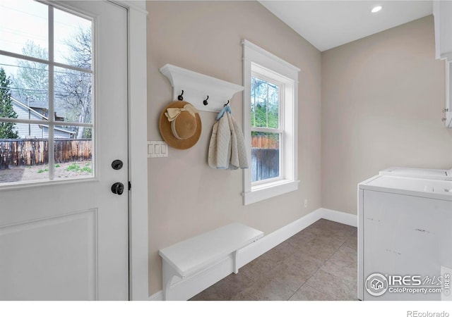 mudroom with baseboards, light tile patterned floors, and washer and dryer