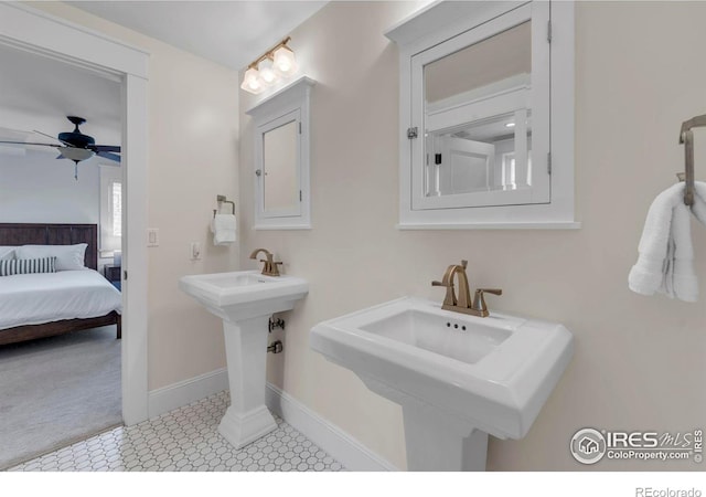 bathroom with a sink, tile patterned floors, a ceiling fan, baseboards, and ensuite bathroom