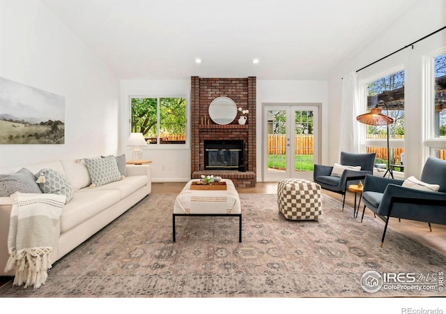 living area featuring a fireplace, recessed lighting, a healthy amount of sunlight, and wood finished floors