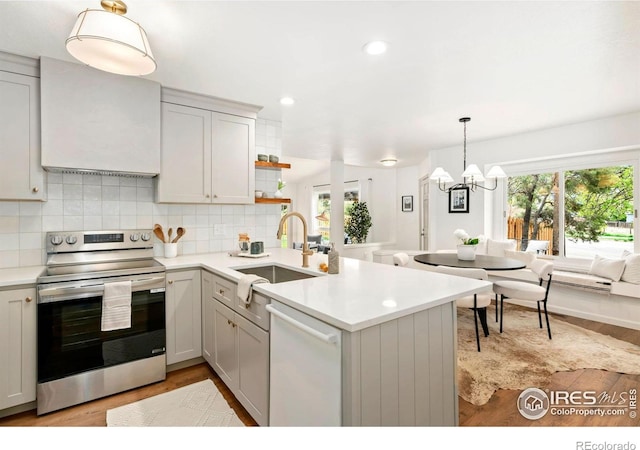 kitchen with dishwasher, a sink, light countertops, stainless steel range with electric cooktop, and light wood-style floors