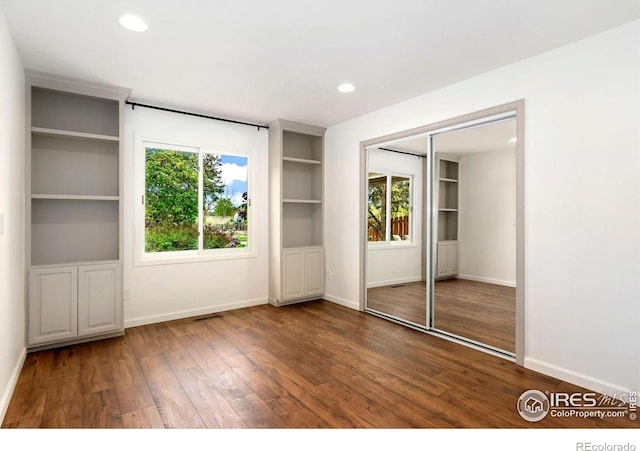unfurnished bedroom featuring hardwood / wood-style floors, recessed lighting, baseboards, visible vents, and a closet