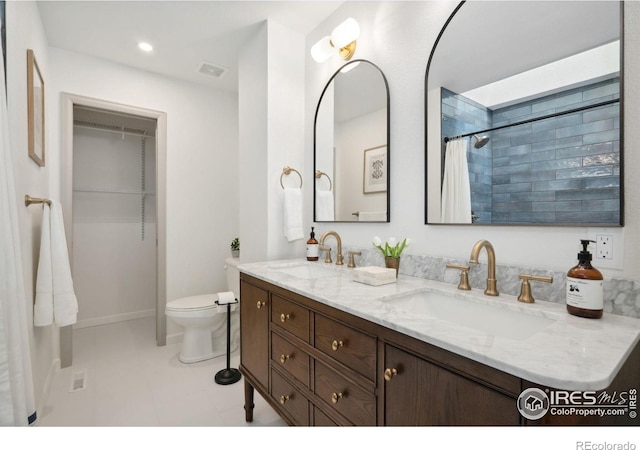 full bath with a sink, toilet, double vanity, and visible vents
