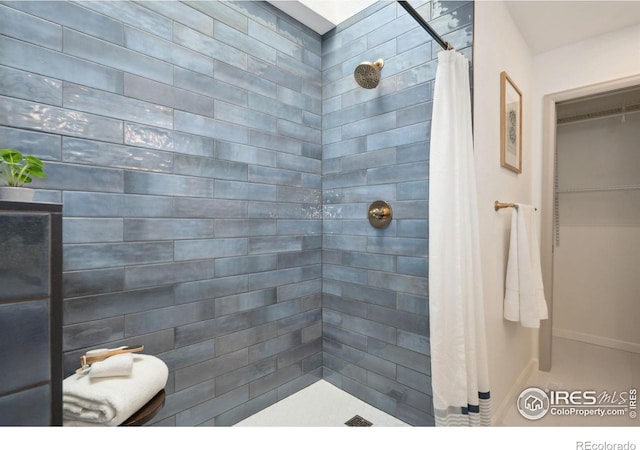full bath featuring baseboards and tiled shower