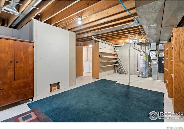 unfinished basement featuring water heater, heating unit, and washing machine and dryer