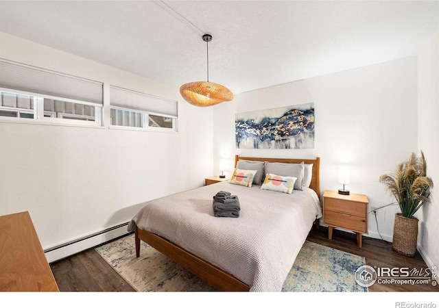 bedroom with baseboards, wood finished floors, and baseboard heating